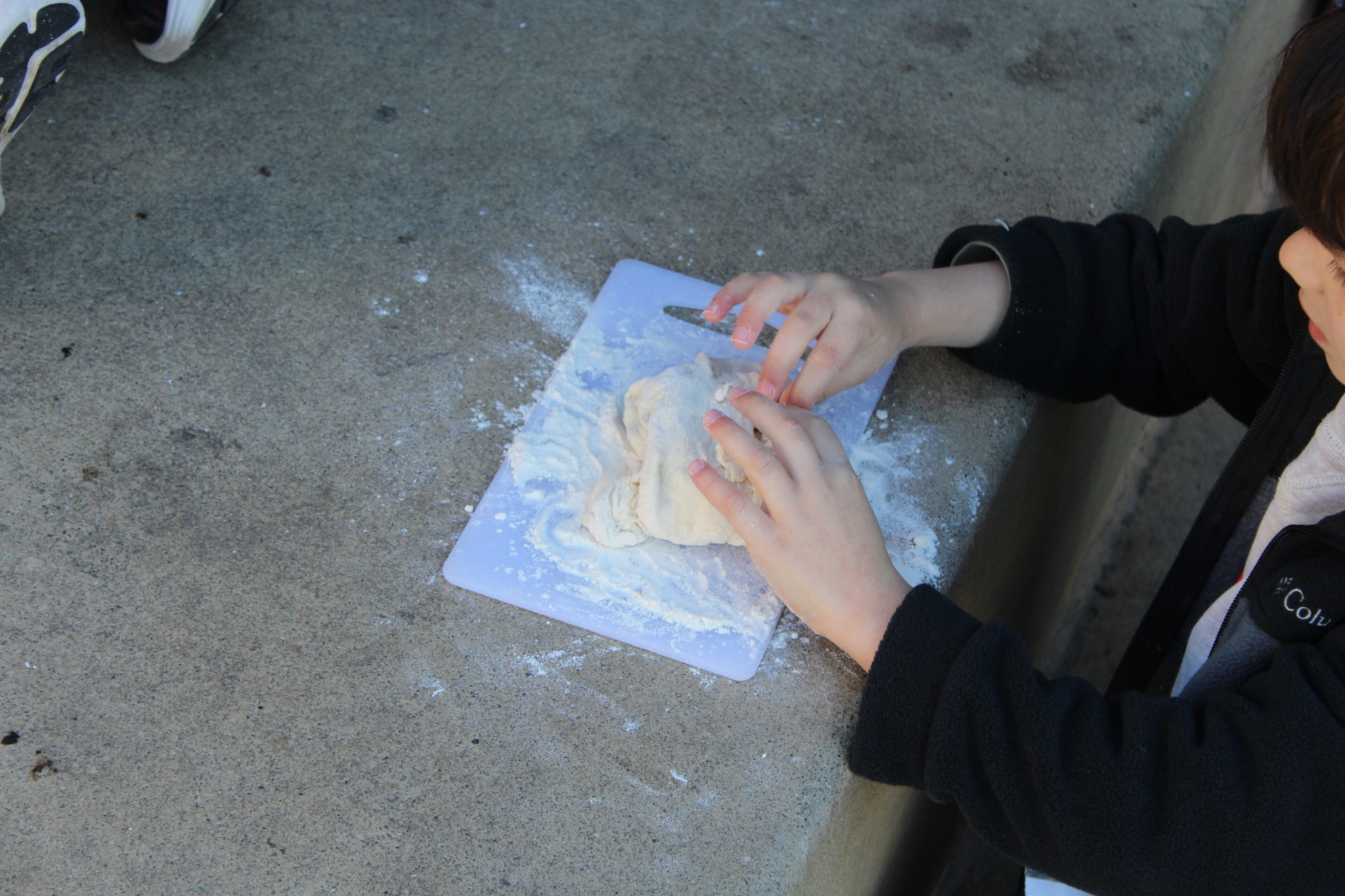 A child's hands kneading bread dough.