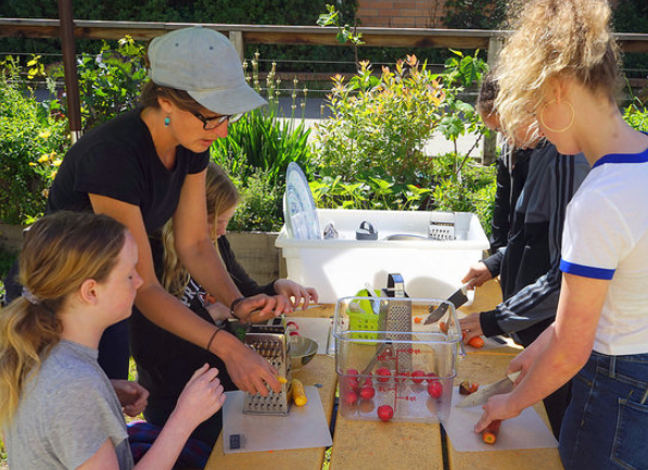 Students learn knife and grating techniques with rainbow carrots in a Berkeley garden classroom.
