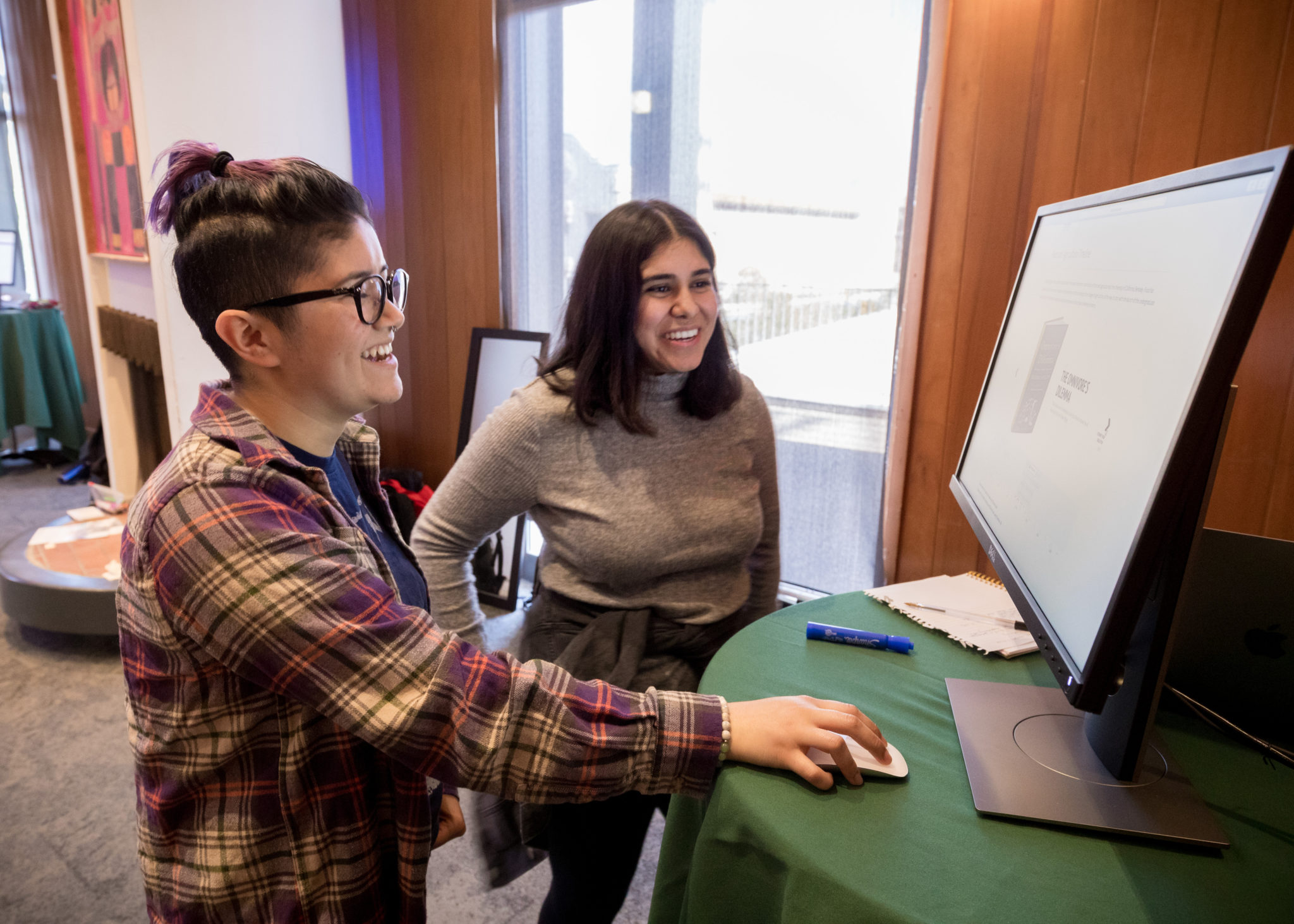 Two students standing at a computer.